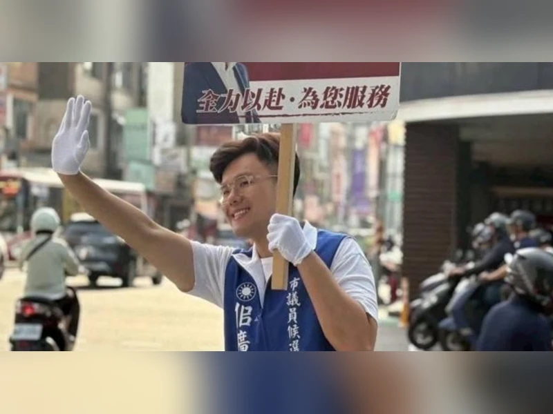 佀廣洋穿著市議員候選人背心，在路口舉手向民眾拜票