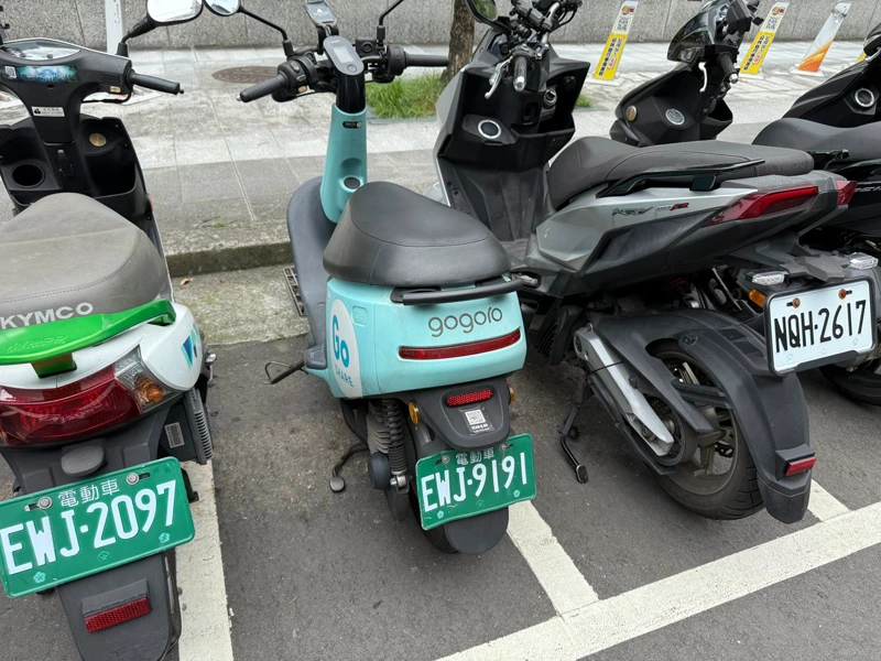 停車格裡幾台機車的綠色電動機車車牌與白色車牌