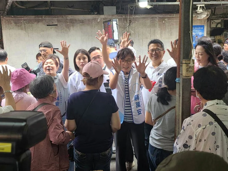 石舫亘在市場走道上向民眾揮手，旁邊圍著支持者和攝影記者