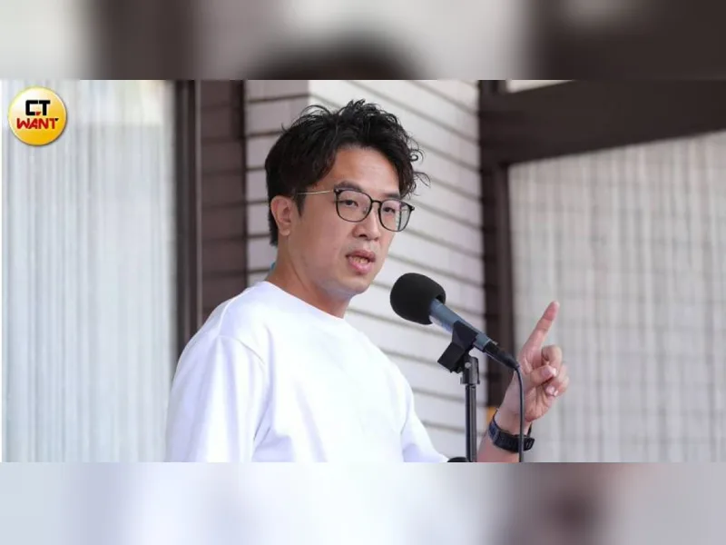 沈伯洋穿白色上衣對著麥克風說話，右手食指比向前方
