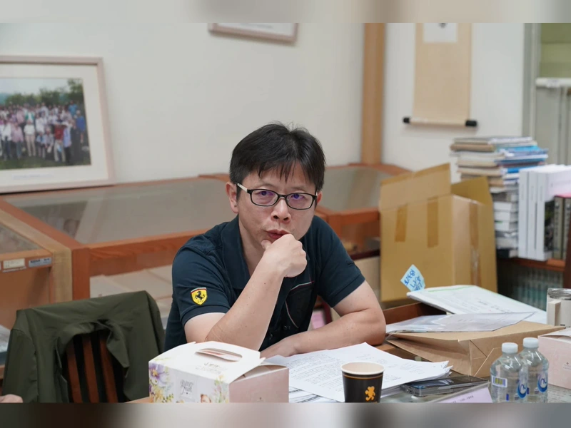 作家許榮哲坐在辦公桌前托著下巴
