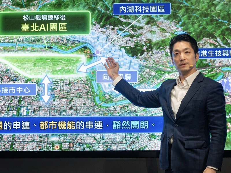蔣萬安在記者會上指著簡報地圖，說明松山機場遷移後的臺北AI園區位置與內湖科技園區的相對關係