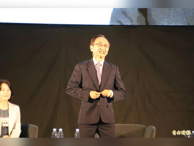吳子嘉穿西裝站在台上演講